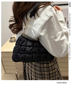 Detail of black quilted cloud bag with glossy finish and elegant golden chain strap