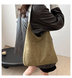 Detail view of large dark olive suede tote bag styled with a black leather jacket