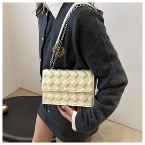 Detail of cream white quilted crossbody bag with 3D diamond texture and chain strap