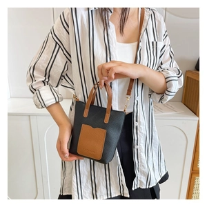 Close-up of a mini black and brown litchi pattern leather crossbody bag on a model