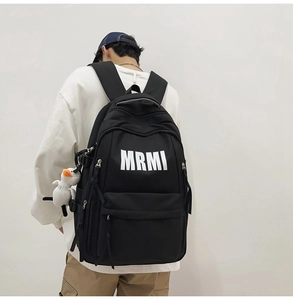Detail view of large capacity black backpack with MRMI print and plush duck pendant