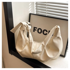 Close-up of beige pebble leather hobo bag featuring a decorative knotted shoulder strap
