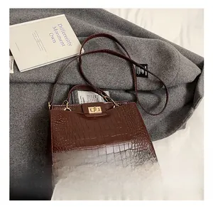 Détail du sac marron foncé avec texture crocodile et fermoir rotatif doré élégant