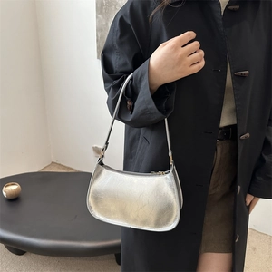 Metallic silver crescent underarm bag with subtle pleated texture and slim shoulder strap