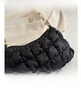 Detail of black quilted cloud bag with plush texture and gold chain strap