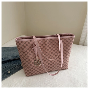 Close-up of pink tote bag with M letter print and decorative gold-tone metal charm