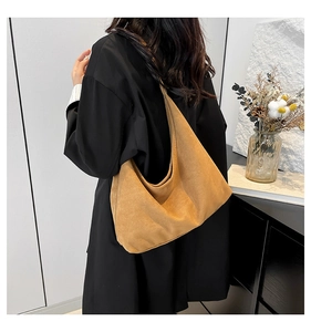 Dettaglio della borsa tote in pelle scamosciata color cammello indossata a spalla da modella