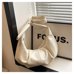 Detail of creamy hobo bag featuring pebbled leather texture and a unique knotted strap