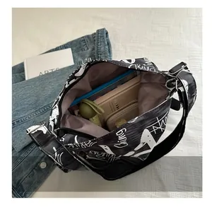 Detail view of large black graffiti canvas bag showing spacious interior with daily items