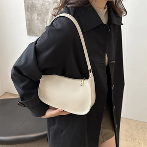 Minimalist cream white crescent armpit bag with golden zipper in a modern lifestyle setting
