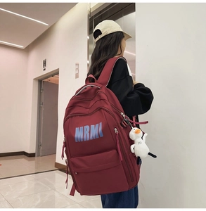 Detail view of burgundy large capacity backpack with MRMI logo and white duck pendant