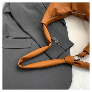 Detail of caramel lychee grain leather hobo bag with knotted shoulder strap and silver ring
