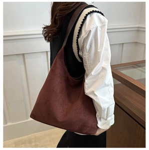 Detail view of deep brown suede tote bag worn over the shoulder by a fashion model