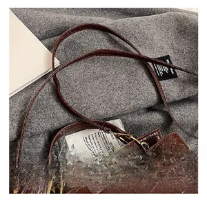 Vue détaillée du relief crocodile marron foncé et du fermoir rotatif doré sur le sac