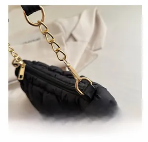 Detailed close-up of glossy black quilted cloud bag featuring a shiny gold metal swivel hook