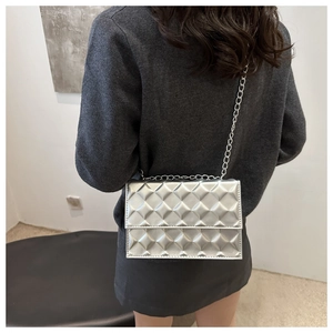 Model wearing a silver quilted chain bag with metallic finish and minimalist design