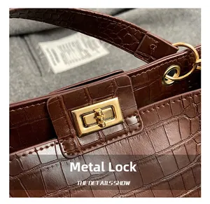 Gros plan du fermoir tournant doré sur sac à main marron avec texture crocodile
