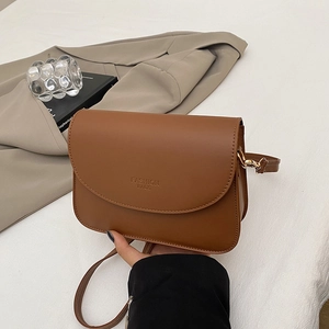 Sac bandoulière marron minimaliste avec rabat incurvé et sangle réglable sur blanc