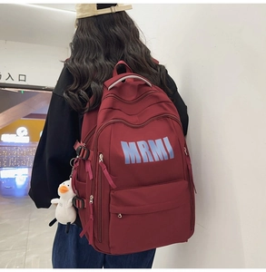 Detail view of burgundy minimalist backpack with side buckles and white duck pendant