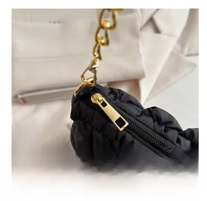 Close-up of smooth gold metal zipper and black quilted texture on casual cloud bag