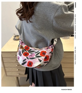 Dettaglio della borsa a tracolla floreale semicircolare con cinturino bianco sul modello