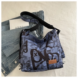 Detail of vintage blue graffiti canvas tote bag with brown leather label and nylon strap
