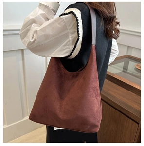 Detailed close-up of large brown suede hobo bag with smooth leather shoulder strap