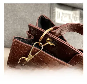Détail du fermoir mousqueton doré sur le sac en cuir marron à texture crocodile chic