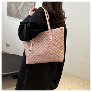 Detail of pink tote bag with M letter prints and golden metallic charm on model's shoulder