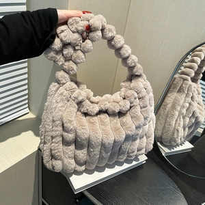 Chic beige plush tote bag with pompom handle and vertical striped quilting for winter