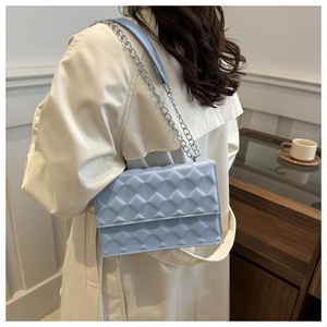 Detail of light blue quilted chain bag with geometric texture and silver metal strap