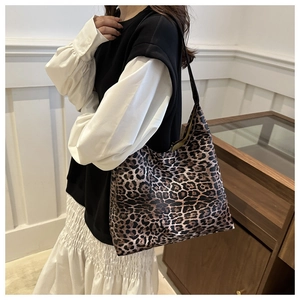 Close-up of leopard print tote bag featuring black leather handles and soft textured fabric