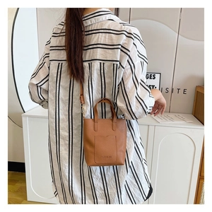Detail view of a brown leather crossbody bag with FASHION logo and thin shoulder strap