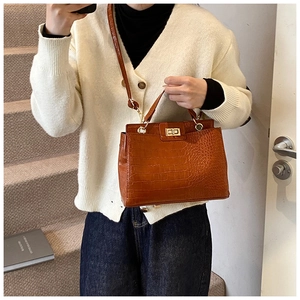 Détail d'un sac à main marron à texture crocodile avec fermoir rotatif doré élégant