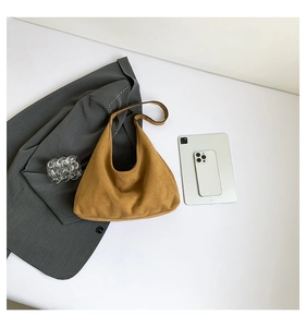 Vista piatta di una borsa tote in pelle scamosciata marrone con blazer grigio e oggetti