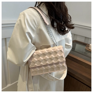 Detail of light pink shoulder bag with 3D geometric texture and silver chain strap