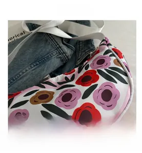 Dettaglio della borsa a mezzaluna con eleganti motivi floreali nei toni rosso e rosa