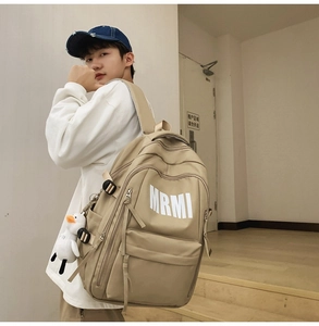 Detailed shot of khaki student backpack with MRMI print and cute duckling pendant charm