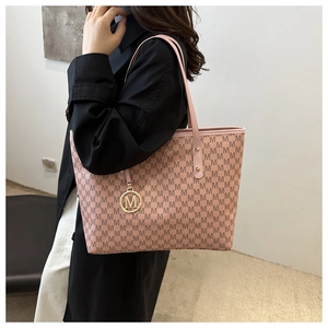 Detail of pink tote bag with M-pattern print and a golden metallic circular charm