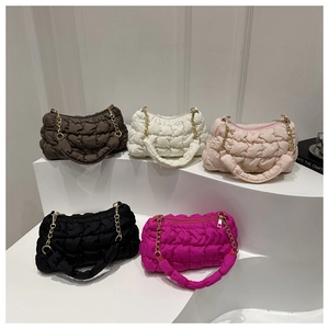 Close-up of five colorful quilted bubble bags with golden chain details on display