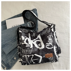 Detail of black canvas tote bag with white graffiti print and adjustable wide strap