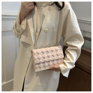 Pink quilted crossbody bag with silver chain strap worn by model in minimalist setting