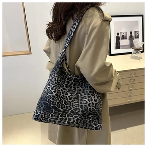 Leopard print tote bag shown on model in khaki coat against minimalist indoor background