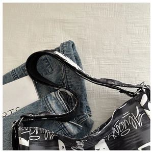 Close-up of black and white canvas crossbody bag with graffiti lettering and strap