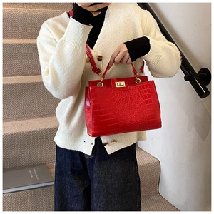 Détail d'un sac rouge motif crocodile avec fermoir doré et bandoulière réglable
