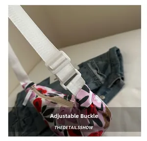 Dettaglio della fibbia regolabile e della tracolla floreale sulla borsa a spalla