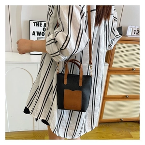 Chic two-tone crossbody tote bag in black and brown leather worn by a model