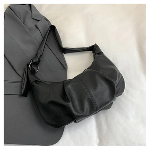 Detail of black pleated croissant bag with lychee texture leather and knotted strap