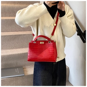Détail du cuir rouge à relief crocodile avec fermoir rotatif doré sur un sac vintage