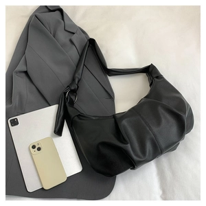 Detail of black pleated leather croissant bag with knotted strap and metal ring buckle